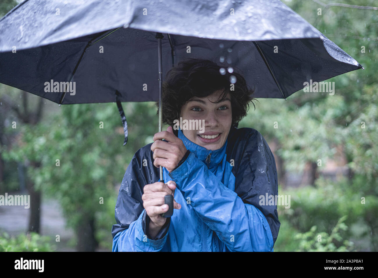 young man standing under the umbrella protect from heavy tropical rain in forests Stock Photo