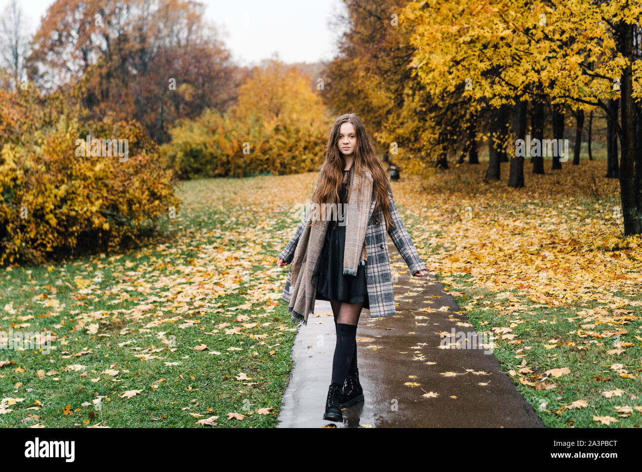 Red-headed curly freckled girl in autumn yellow park. The first snow, wet rain Stock Photo