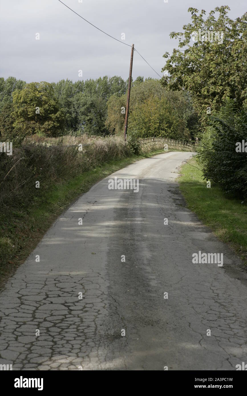 Narrow Winding Country Road with Wooden Fencing and Grass Verges Stock Photo