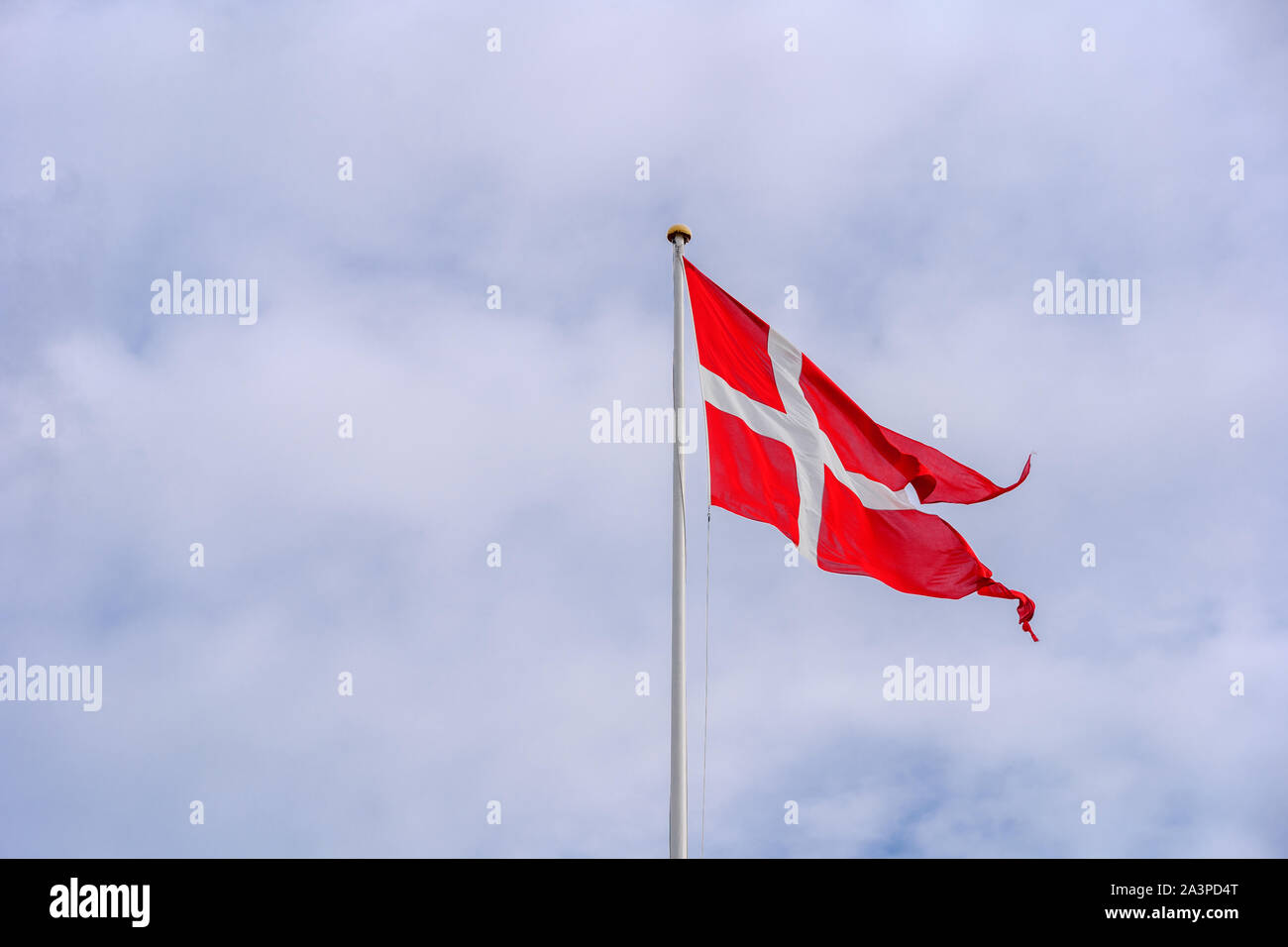 Denmark Flag blowing and waving at strong windy day against cloudy sky. Stock Photo