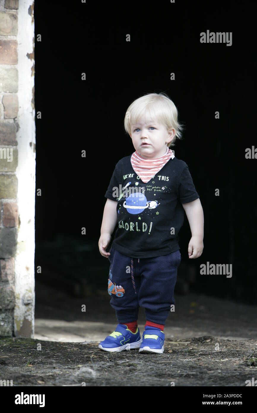 Young Male Toddler Child Standing in Stable Yard Doorway Stock Photo