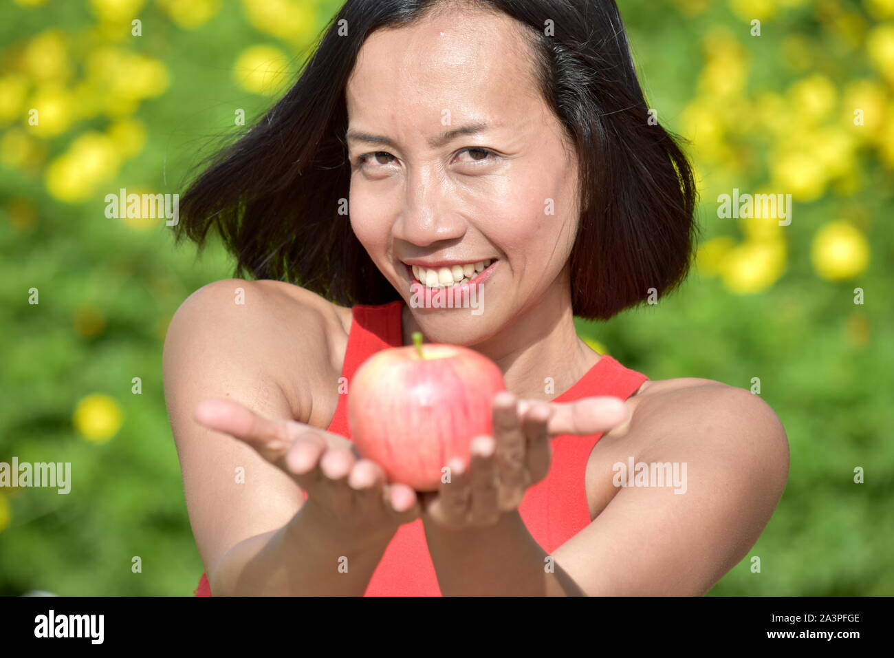 Young Female Smiling With An Apple Stock Photo