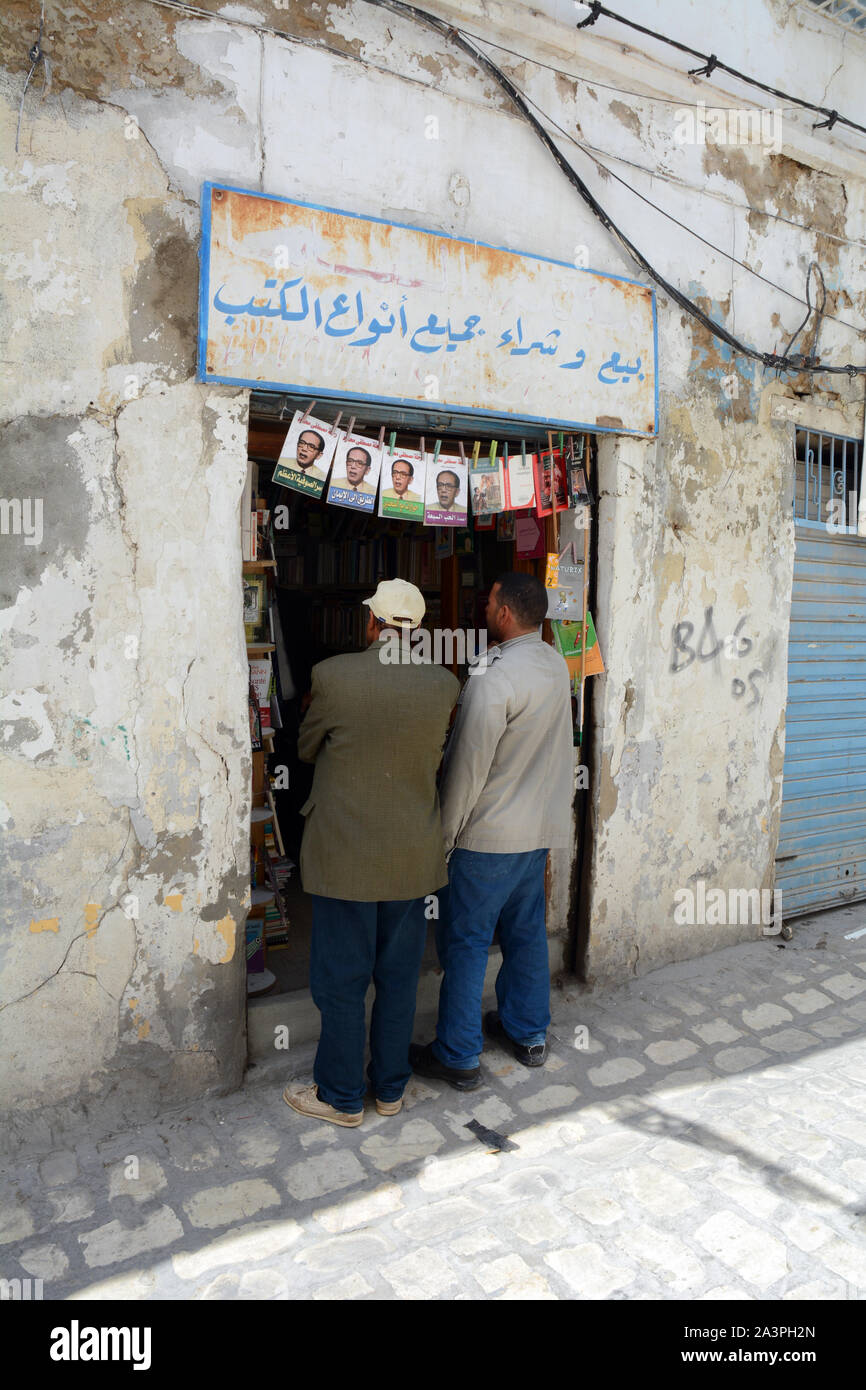 Two Tunisian men standing at the entrance to a bookshop in the market district of the kasbah, in the Medina of Tunis, Tunisia. Stock Photo