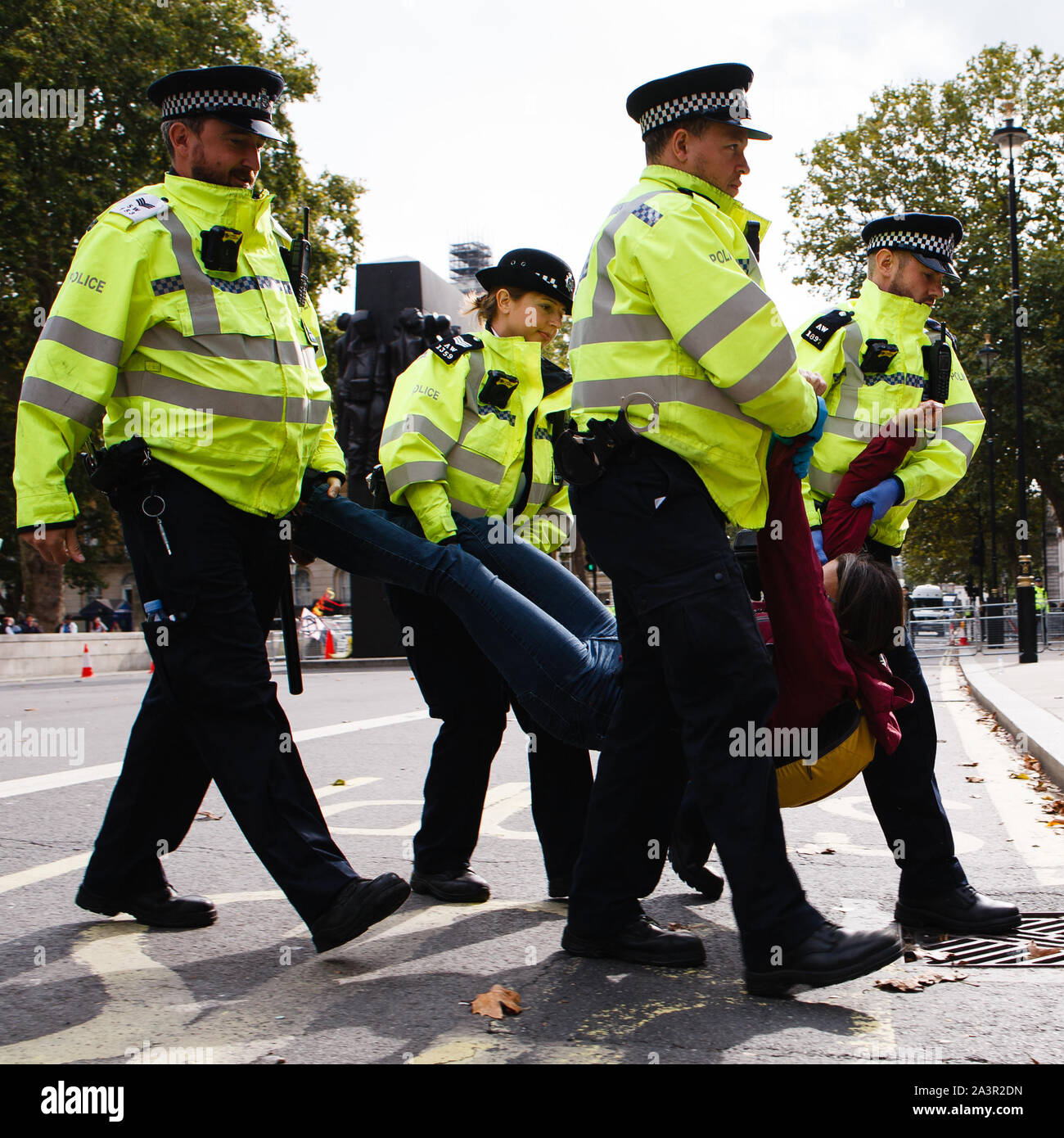 Police officers carry an arrested member of climate change activist movement, Extinction Rebellion (XR) on Whitehall during the third day of the group's 'International Rebellion' in London.Police officers continue to clear demonstrators and tents from sites across Westminster, with activists having been warned about moving to a designated protest area around Nelson's Column in Trafalgar Square or face arrest. Similar blockades by Extinction Rebellion in April, at sites including Oxford Circus and Waterloo Bridge, saw more than 1,000 arrested, a tactic promoted by XR founder Roger Hallam as a m Stock Photo