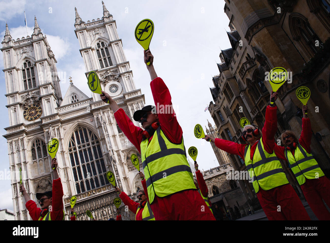 Members of climate change activist movement, Extinction Rebellion (XR) dressed as air traffic controllers, with paddles bearing anti-aviation logos, demonstrating in front of Westminster Abbey during the third day of the group's 'International Rebellion' in London.Police officers continue to clear demonstrators and tents from sites across Westminster, with activists having been warned about moving to a designated protest area around Nelson's Column in Trafalgar Square or face arrest. Similar blockades by Extinction Rebellion in April, at sites including Oxford Circus and Waterloo Bridge, saw m Stock Photo