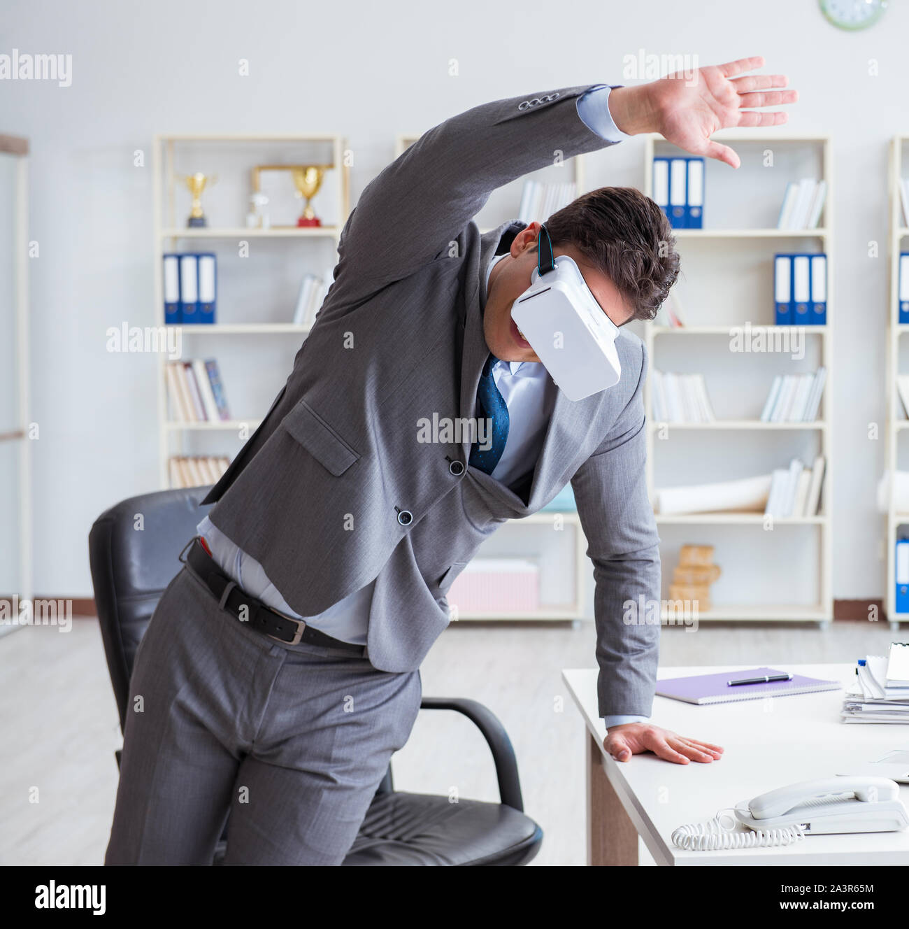 The businessman exercising in office wearing vr glasses Stock Photo - Alamy