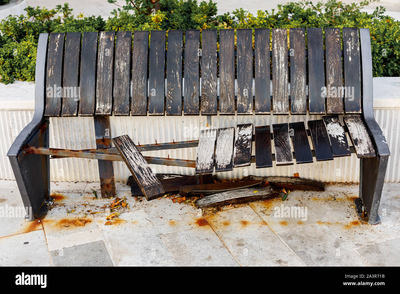 Damaged and broken wooden brown bench on the street, aging or vandalism