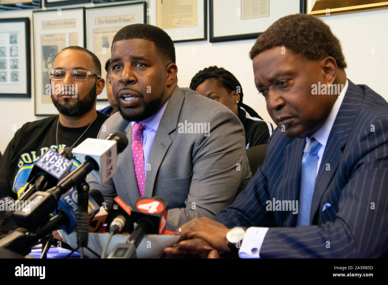 Attorney Adante Pointer speaks alongside Kori McCoy, left, and attorney John Burris, right, to announce a lawsuit for a fatal police shooting. Stock Photo
