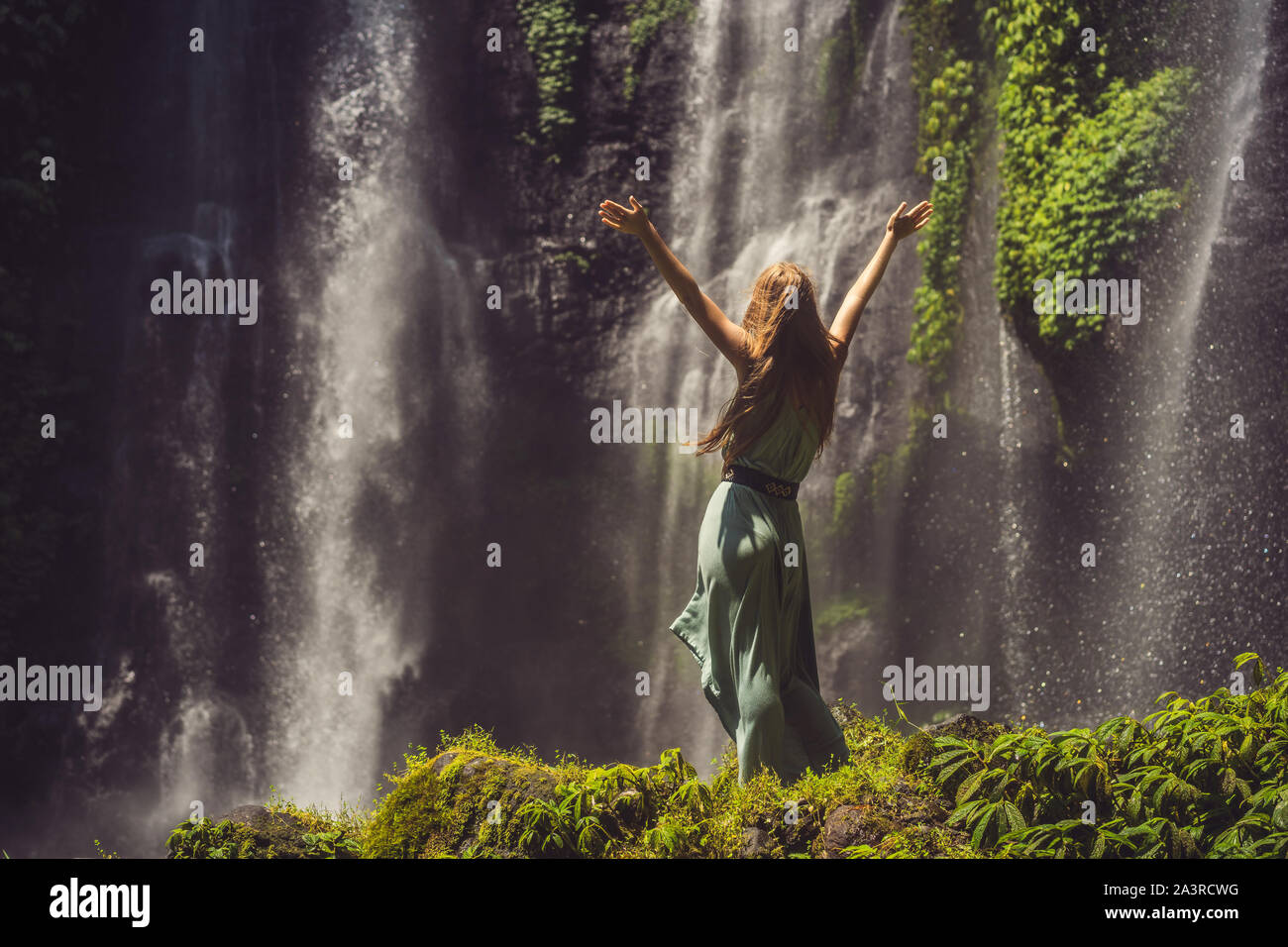 Woman in turquoise dress at the Sekumpul waterfalls in jungles on Bali ...