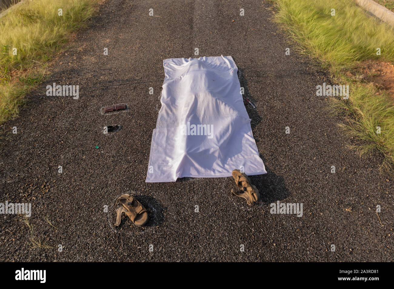 Concept of crime murder scene, High angle view of chalk outlined death body under white cloth on road Stock Photo