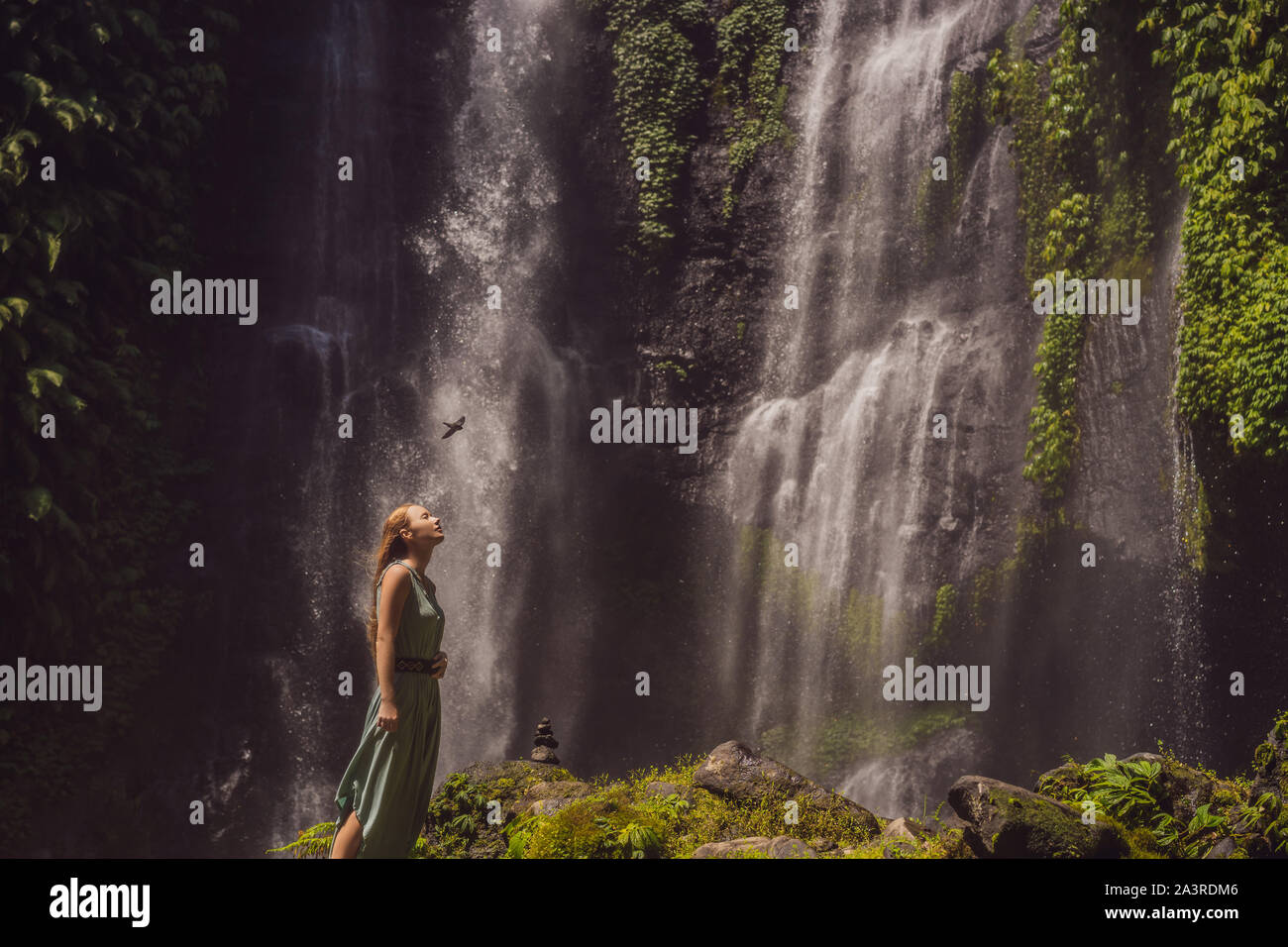 Woman in turquoise dress at the Sekumpul waterfalls in jungles on Bali ...