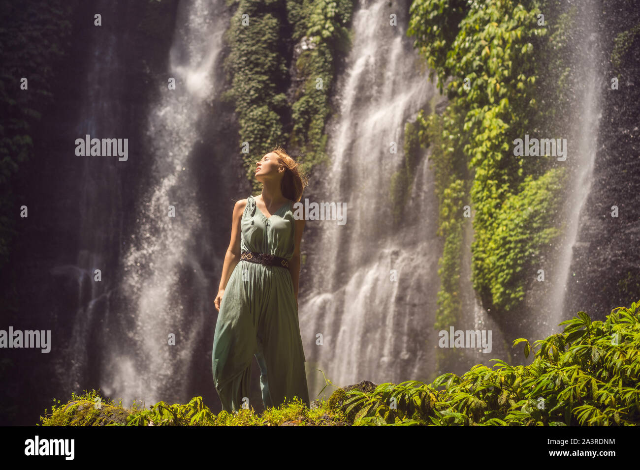 Woman in turquoise dress at the Sekumpul waterfalls in jungles on Bali ...