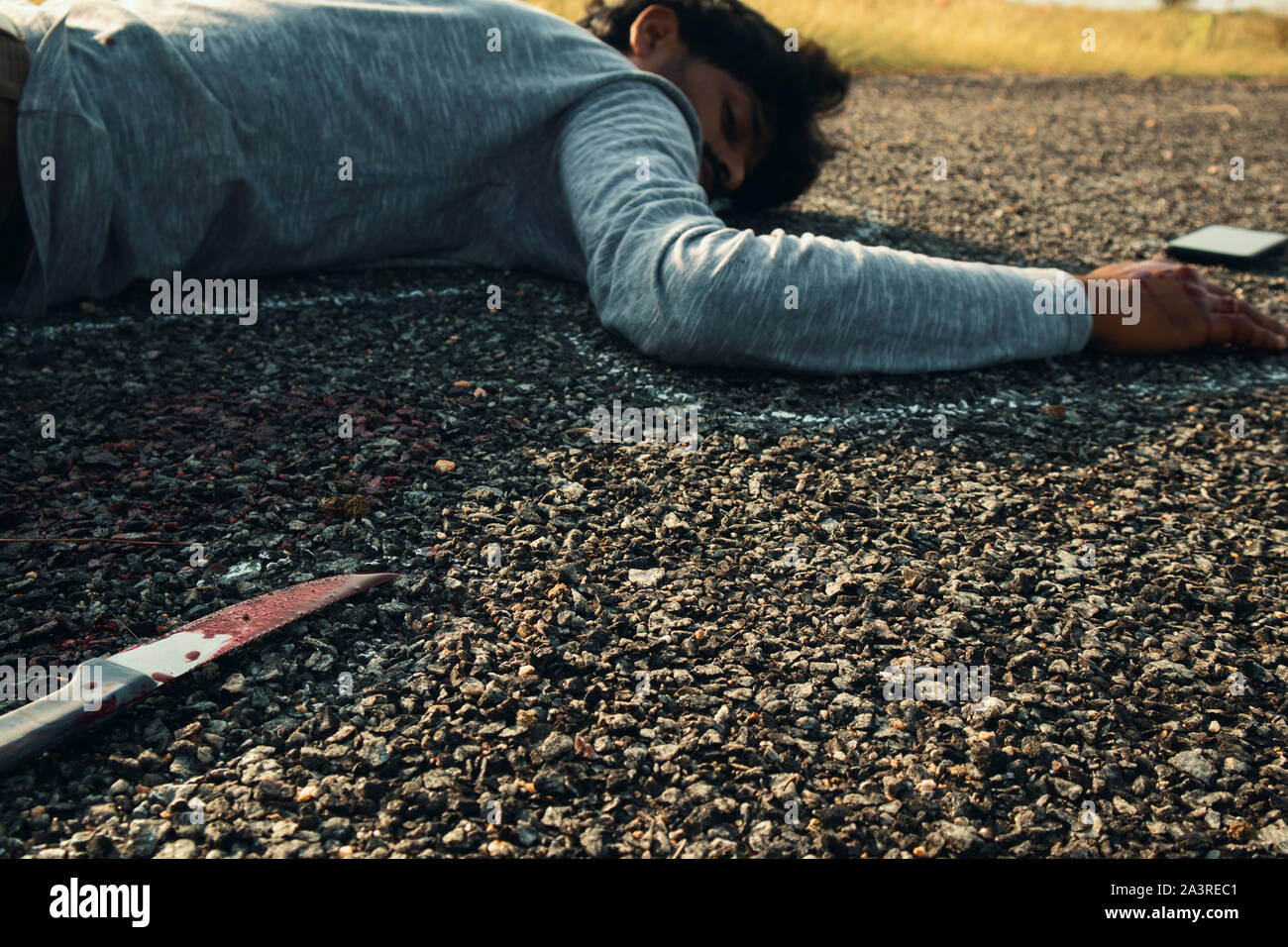 Concept of Crime murder scene, Selective focus of bloody knife on the road with chalk outlined dead body as background laying on Road Stock Photo