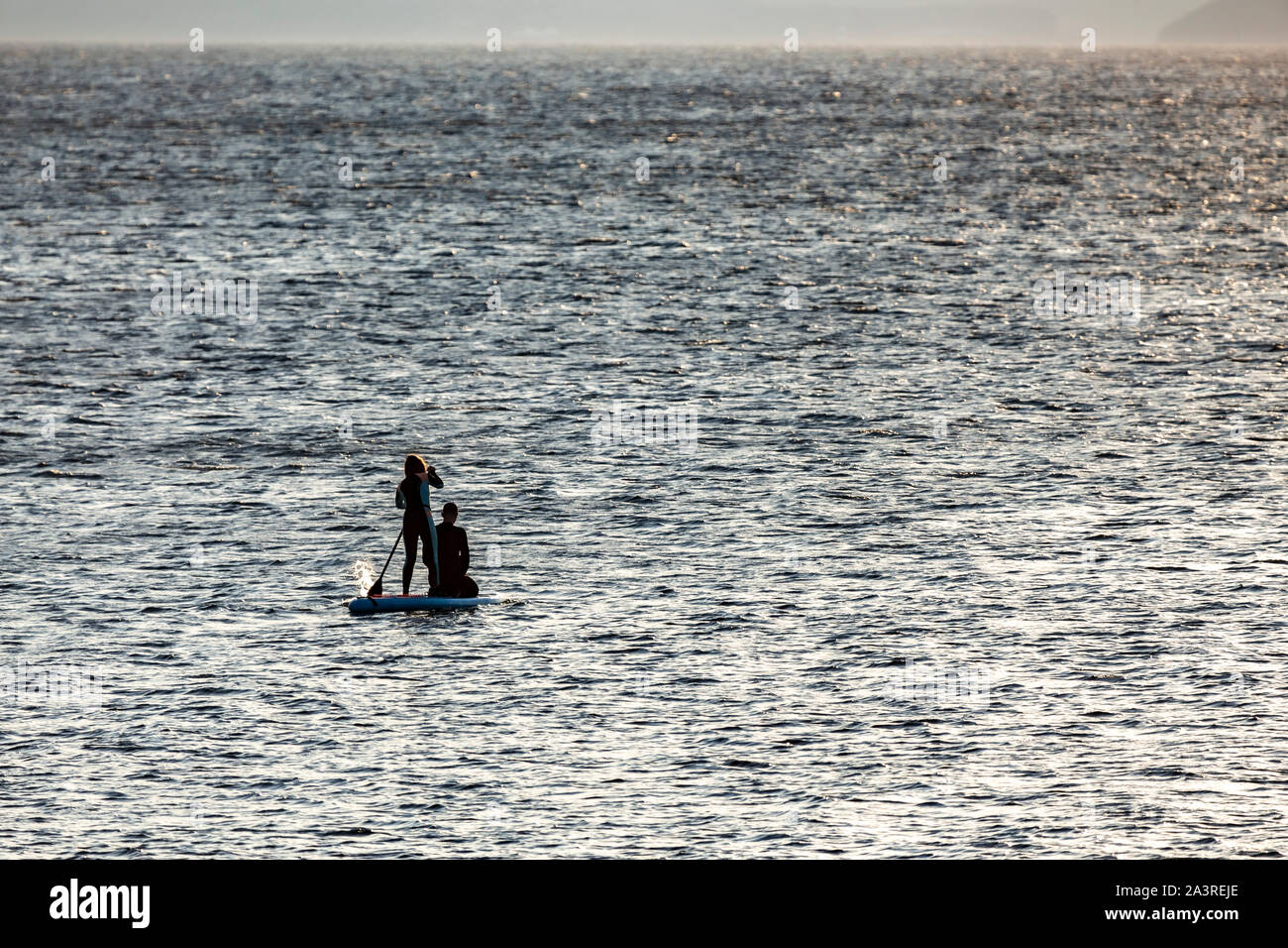 Couple paddleboarding off Llanddona beach, Anglesey, North Wales Stock Photo