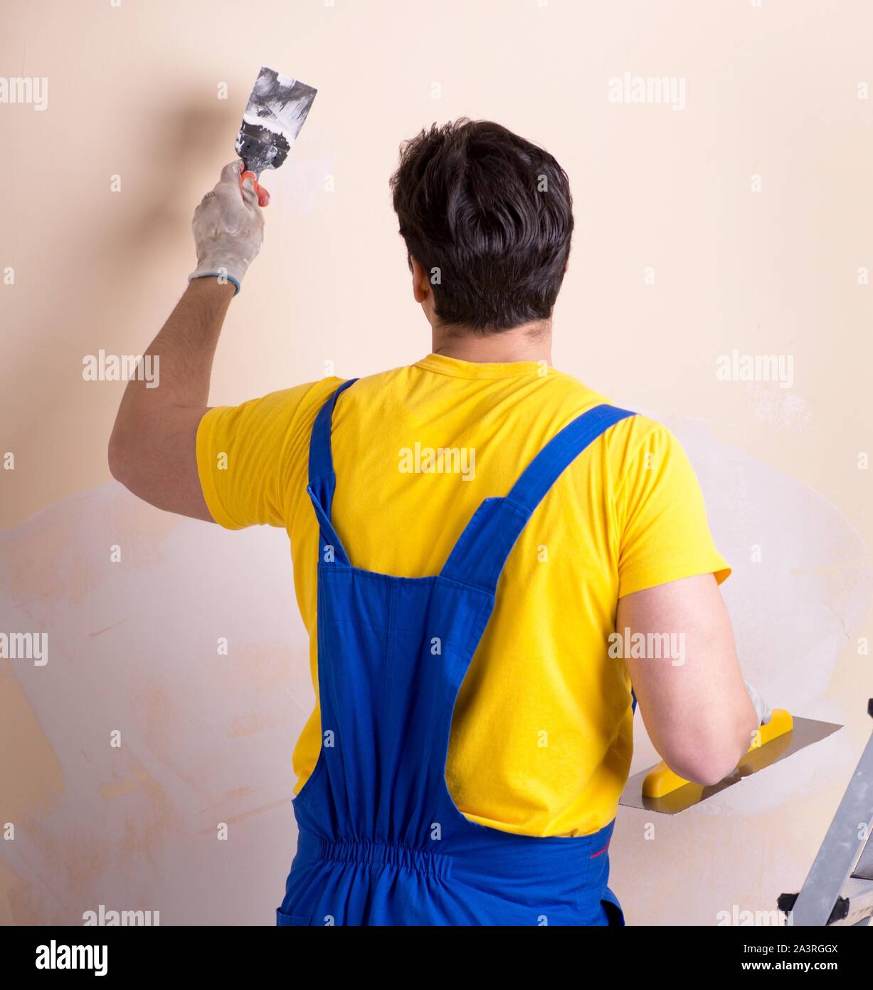 The young contractor employee applying plaster on wall Stock Photo