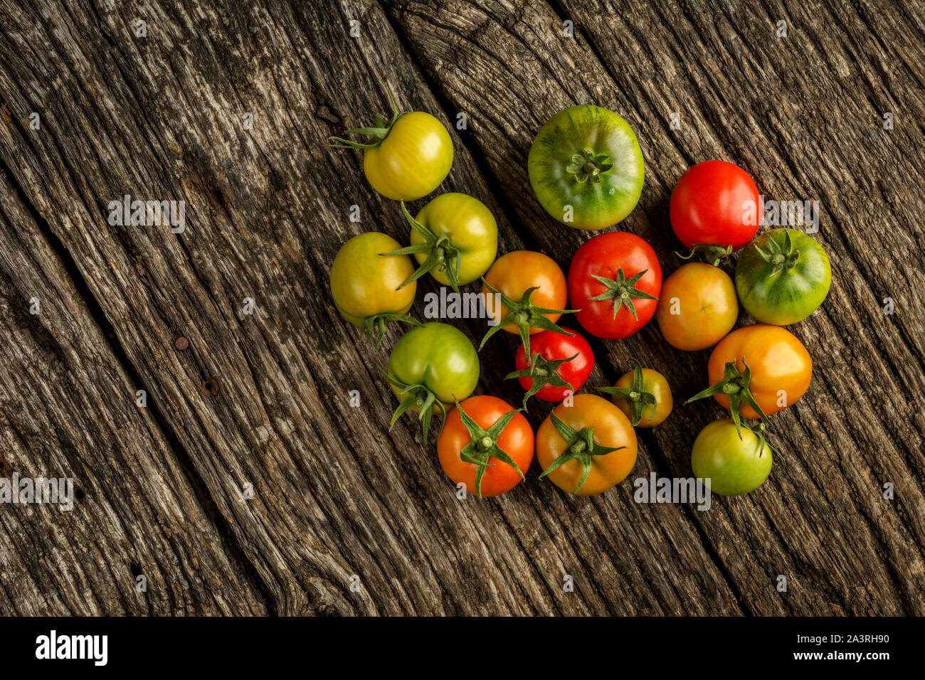 Flat-lay of fresh colorful ripe Fall or Summer heirloom tomatoes variety over rustic background, top view, copy space. Stock Photo
