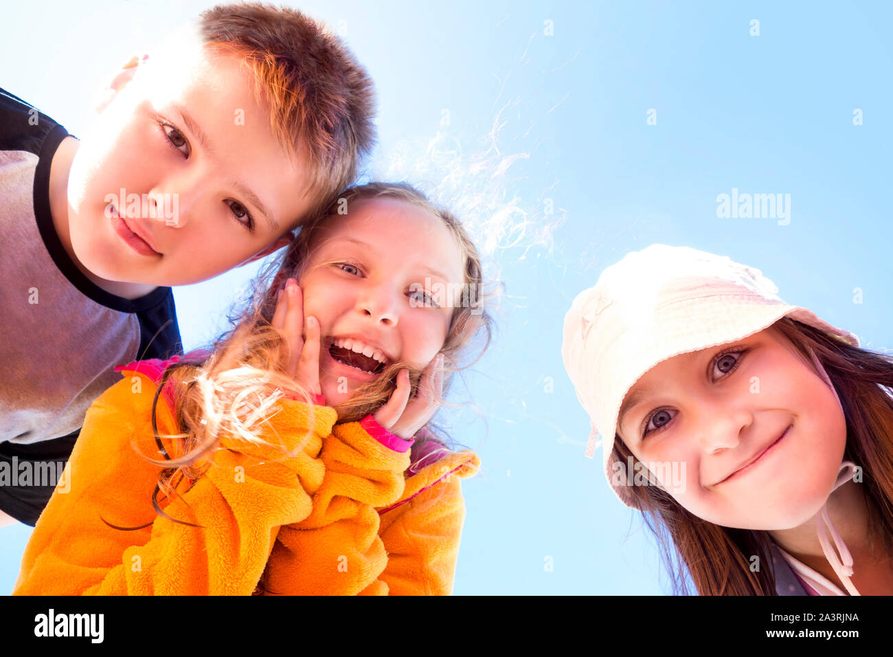 Group of three happy, surprised children looking down at the viewer. Stock Photo