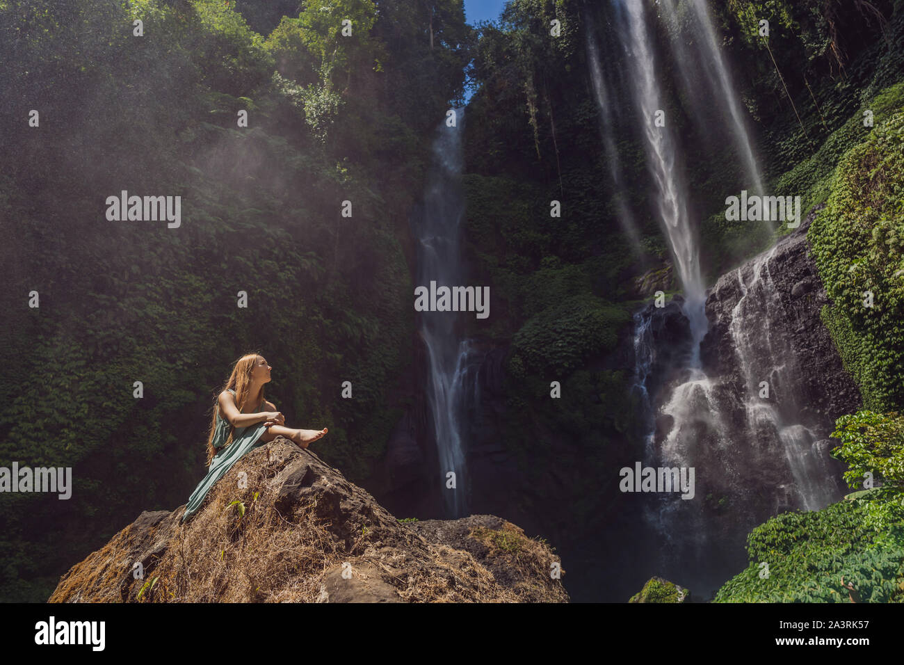 Woman in turquoise dress at the Sekumpul waterfalls in jungles on Bali ...
