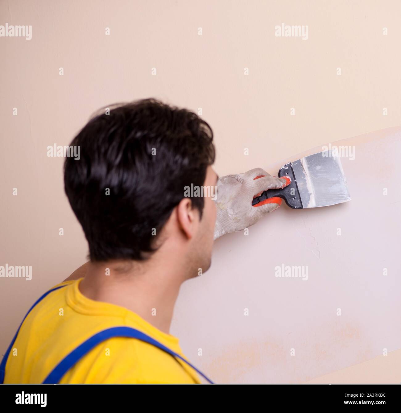 The young contractor employee applying plaster on wall Stock Photo