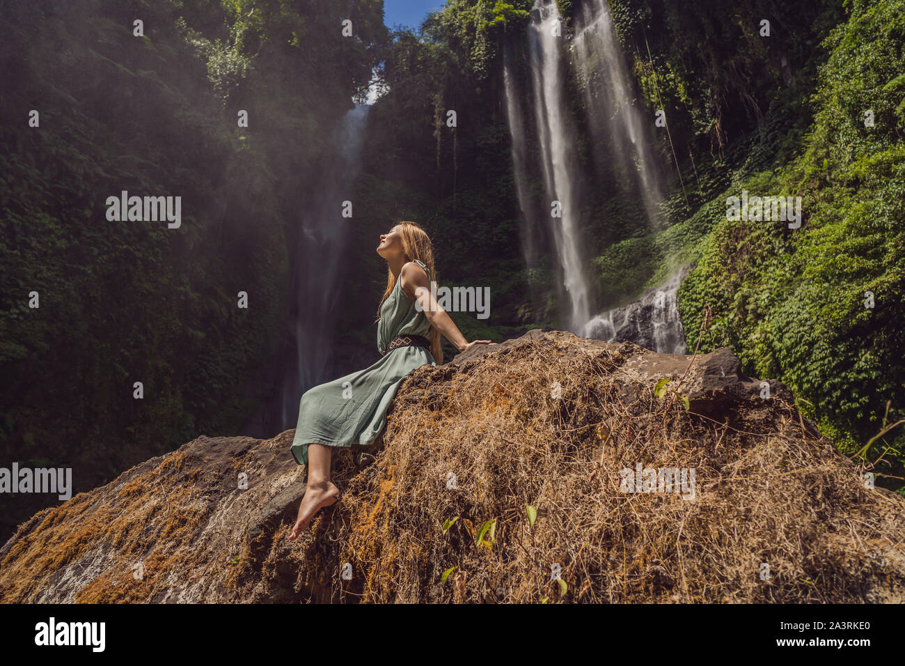 Woman in turquoise dress at the Sekumpul waterfalls in jungles on Bali ...