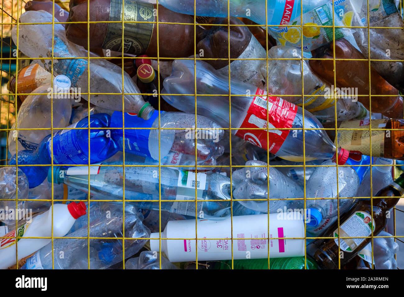 Used and disposed plastic bottles collected in a box with yellow grid. Waste sorting and recycling concept. Close-up view in full frame Stock Photo