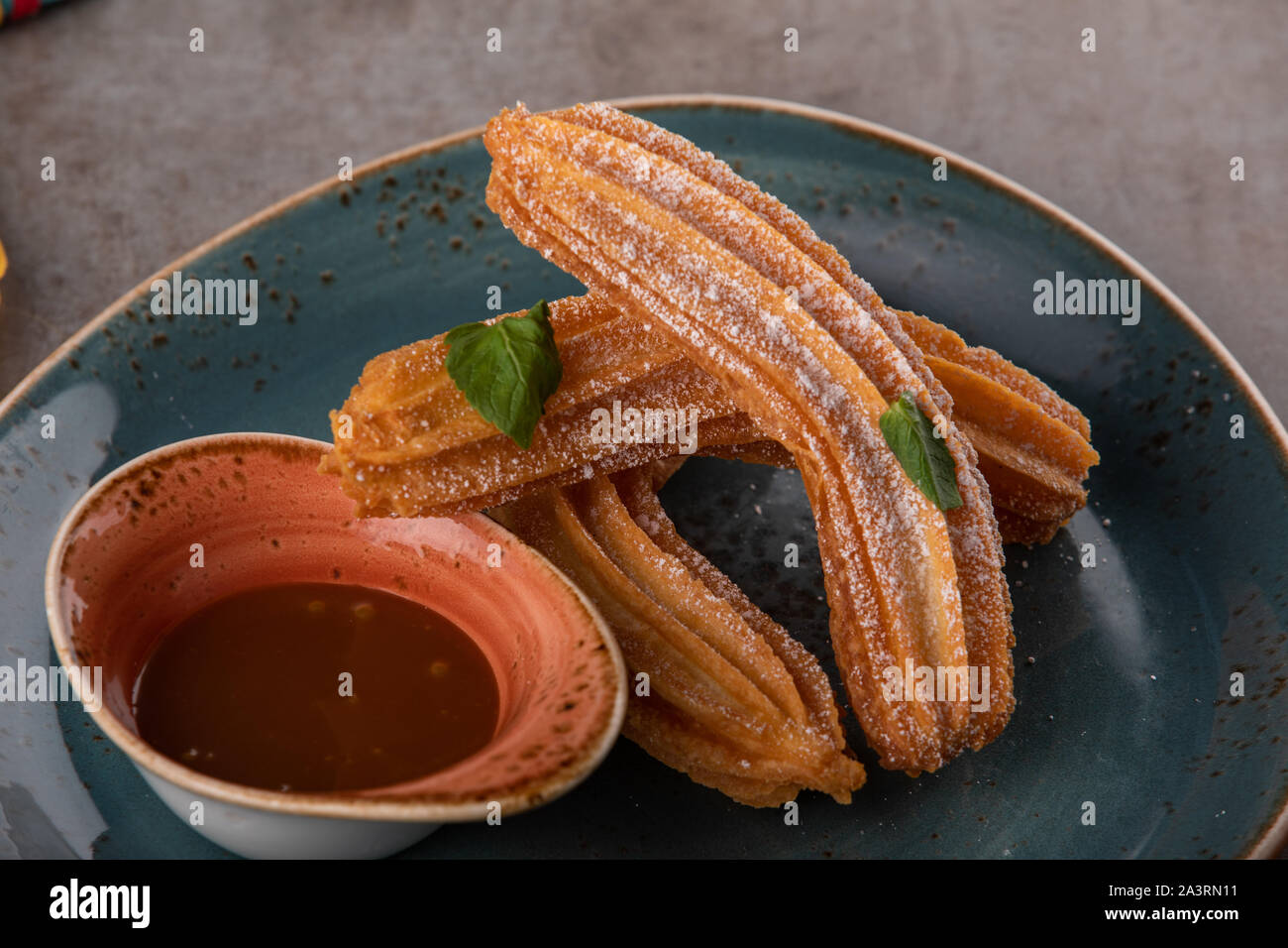 Churros with sugar and chocolate sauce, mint. Stock Photo