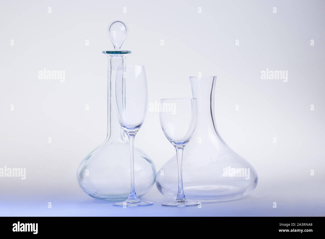 Empty decanters with wine glass and clipping path on light-blue background. Stock Photo