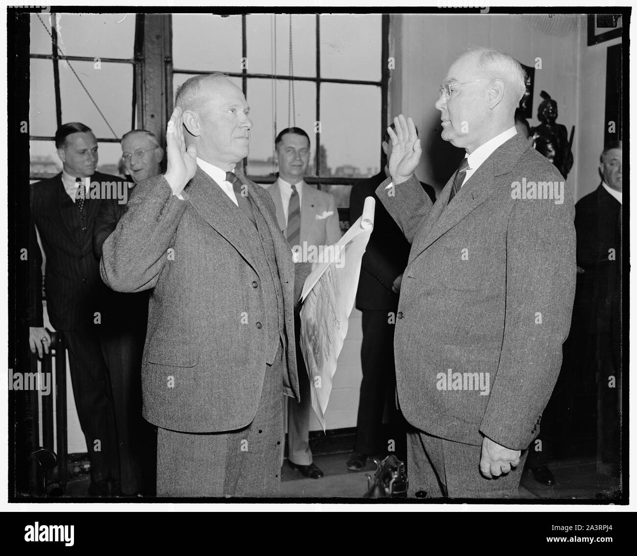 Takes oath as U.S. Marine Corps Paymaster. Washington, D.C., May 2. Maj. Gen. Thomas Holcomb, (left) Commandant of the U.S. Marine Corps, administering the Oath of Office to Brig. Gen. Russell B. Putnam, new Paymaster of the Devil Dogs. He succeeds Brig. Gen. Harold C. Reisinger, 5/2/38 Stock Photo