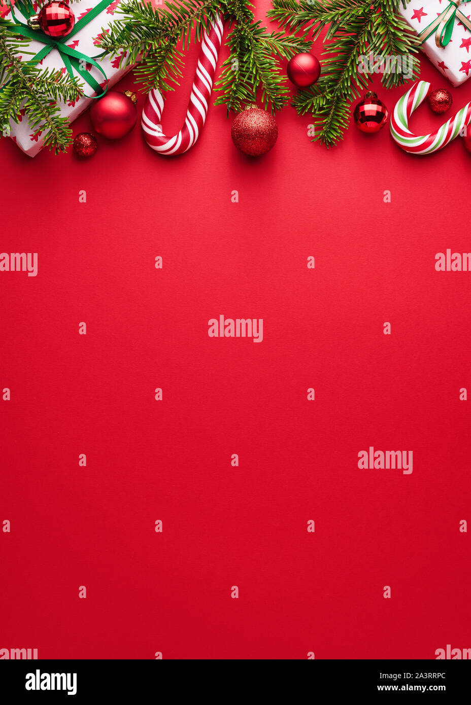 Red background. Copy space for Christmas creep. Border of fir branches, gifts, Christmas balls and candy cane Stock Photo