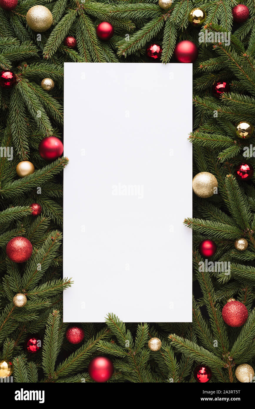 Christmas and New Year background with copy space on note paper. Festive frame of fir branches and Christmas balls Stock Photo