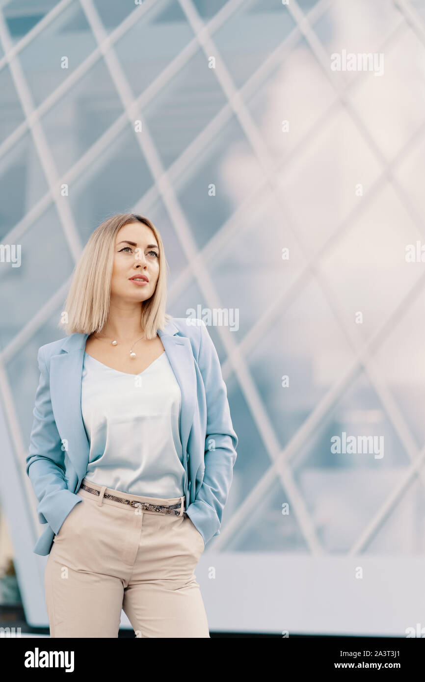 Successful business woman in blue suit. Beautiful young female executive in an urban setting near office building Stock Photo