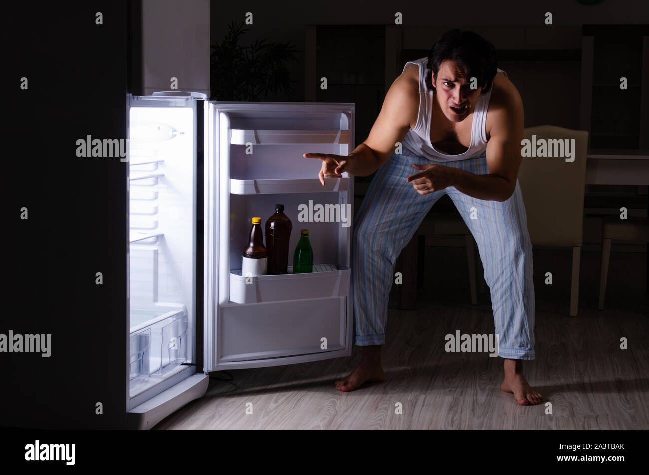 The man breaking diet at night near fridge Stock Photo