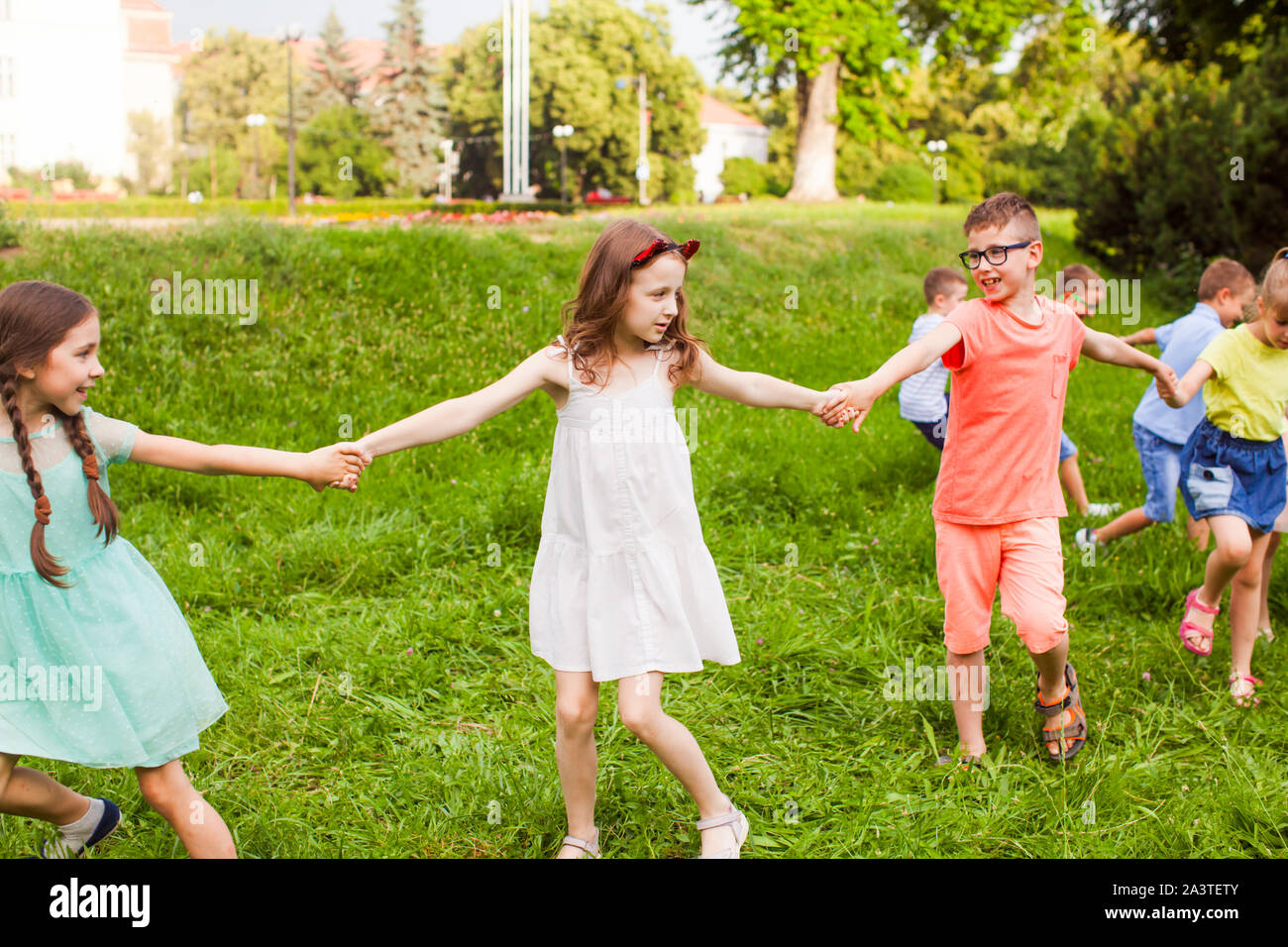 Happy children holding hands and playing outdoors game Stock Photo - Alamy
