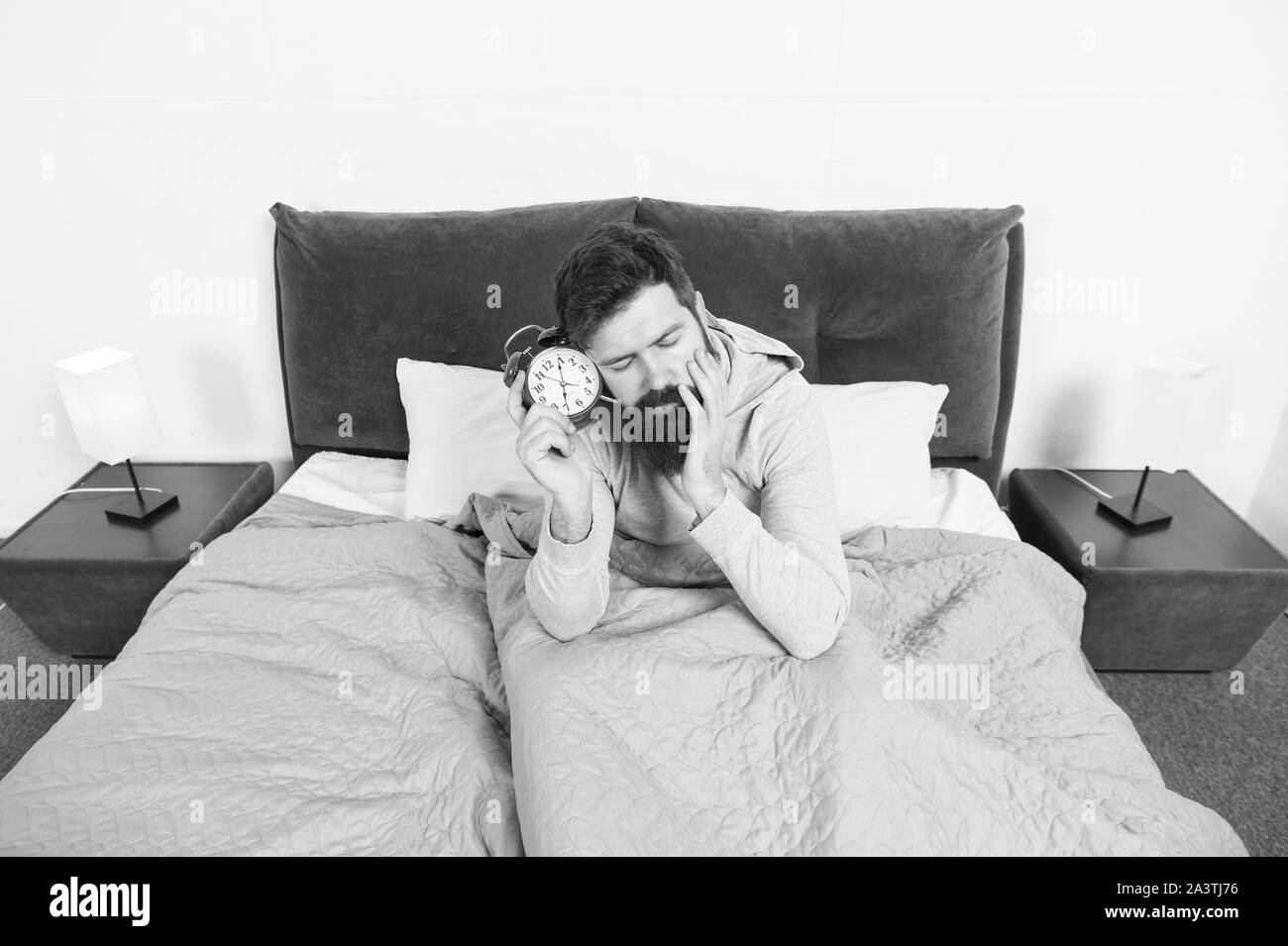 Again unhappy in morning. Tips for waking up early. Man bearded hipster sleepy face waking up. Daily schedule for healthy lifestyle. Alarm clock ringing. Problem early morning awakening. Get up early. Stock Photo