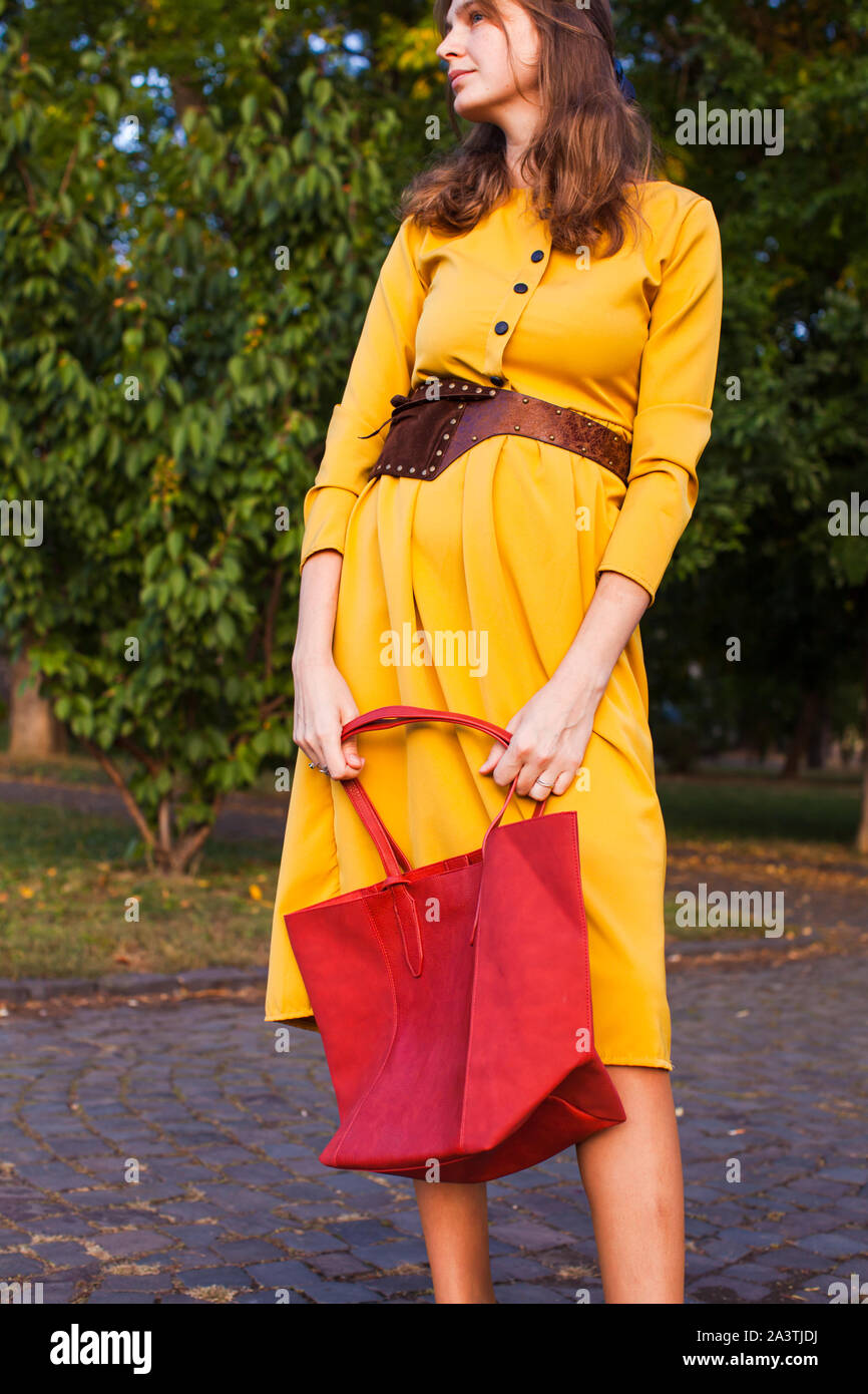 Fashion woman wearing yellow dress and holds red trendy handbag Stock ...