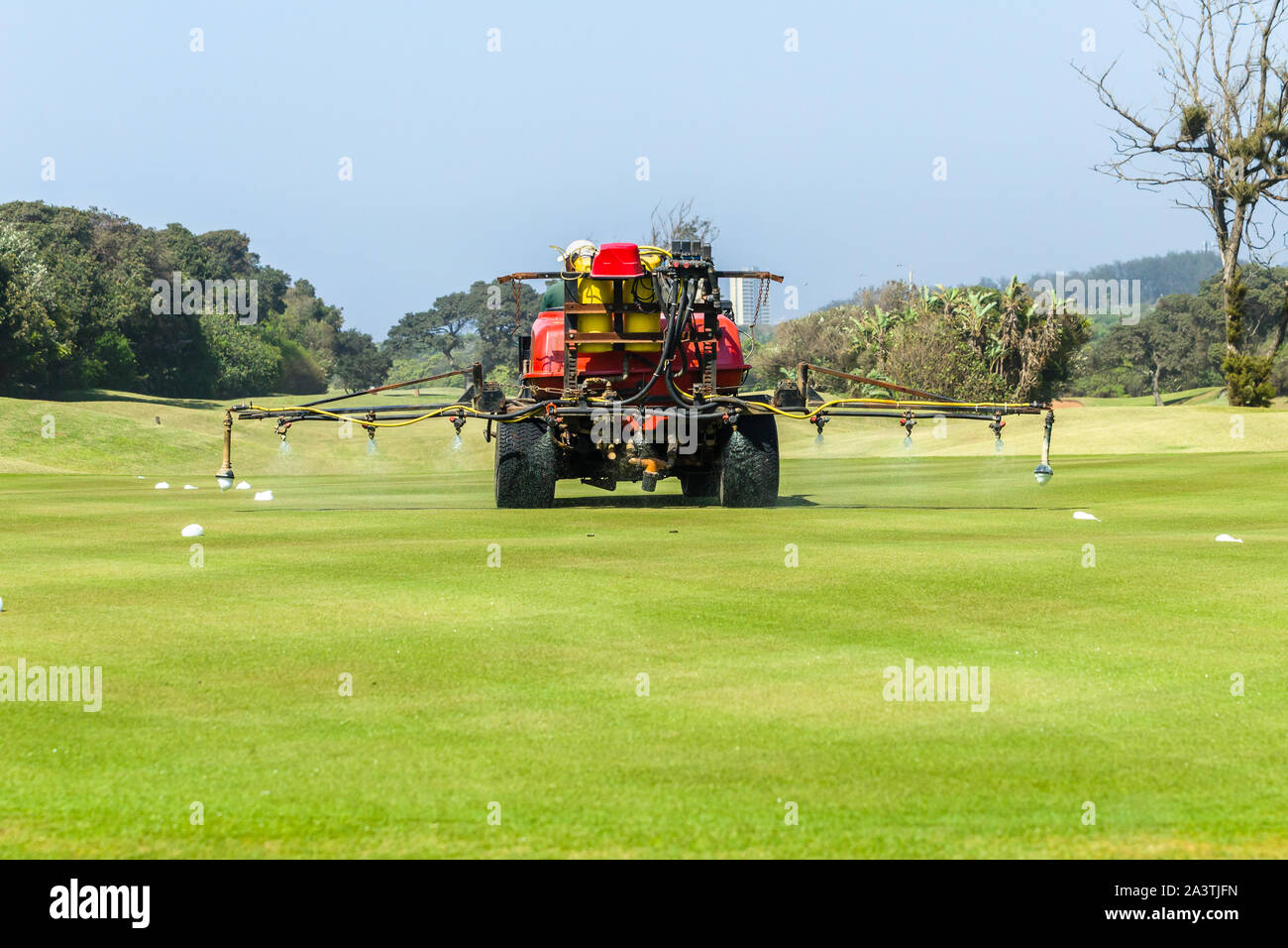 Golf course hole machine operator spraying treatment on grass putting