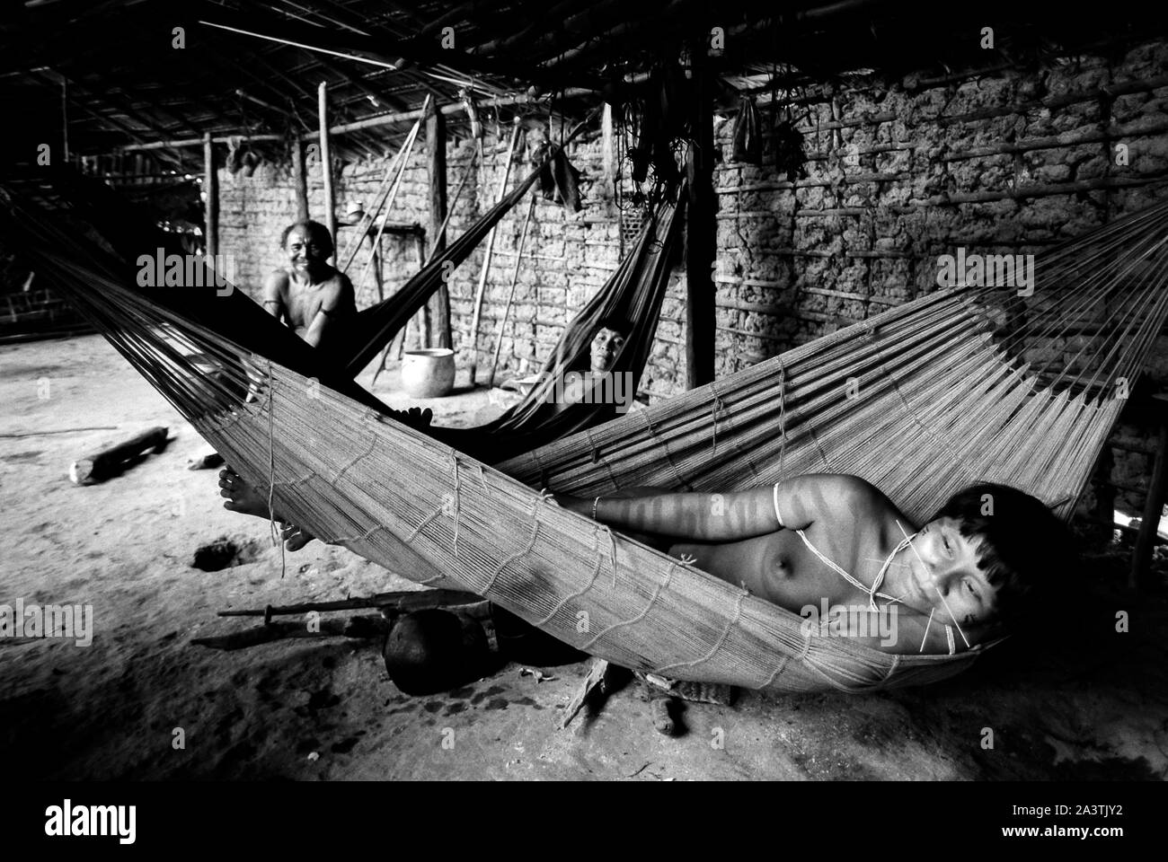 Brazil, Amazonia, Roraima: a family rests lying on the hammocks inside the Shabono. Stock Photo