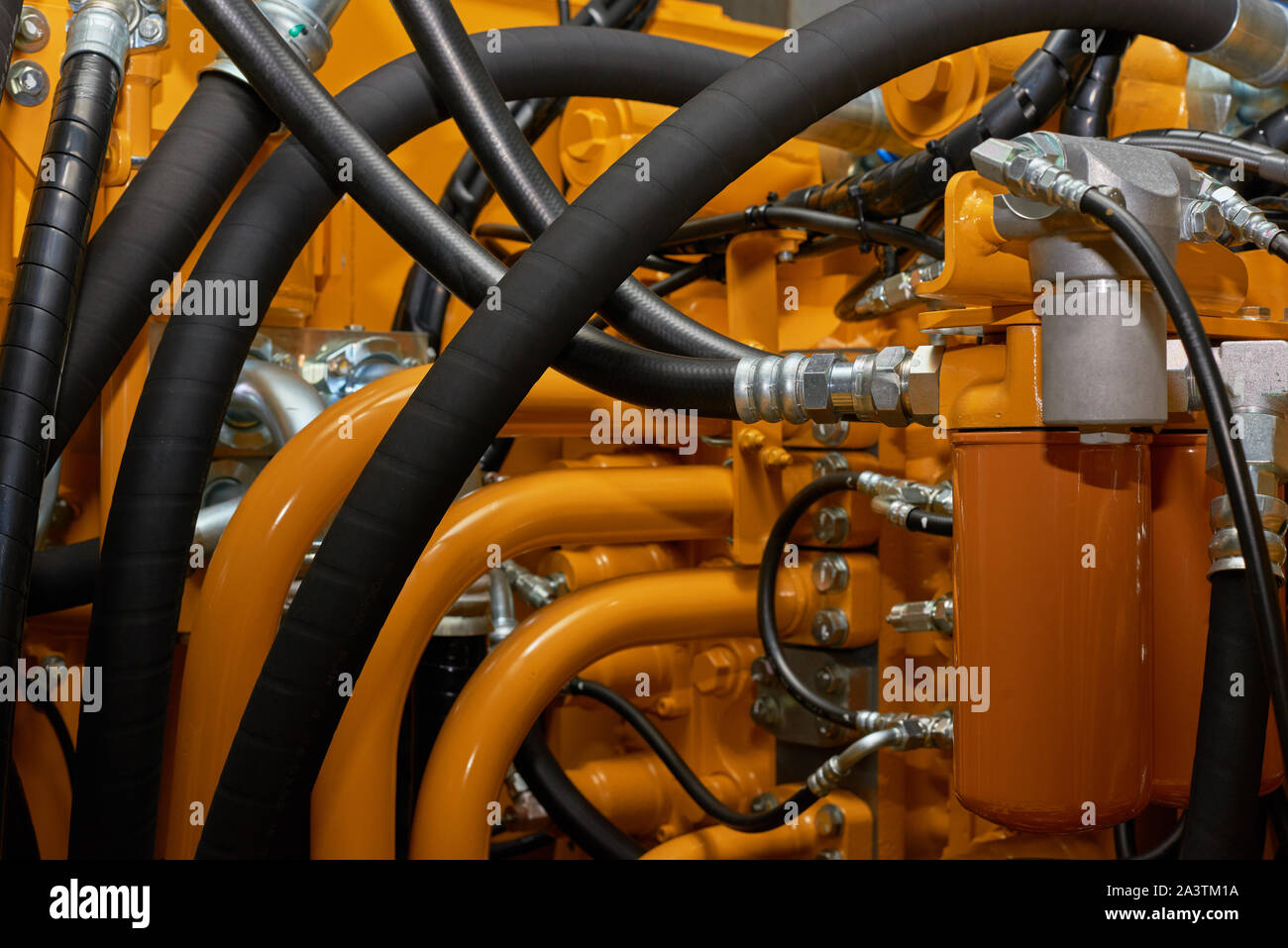 Close up view of hydraulic pipes of heavy industry machine. Low key