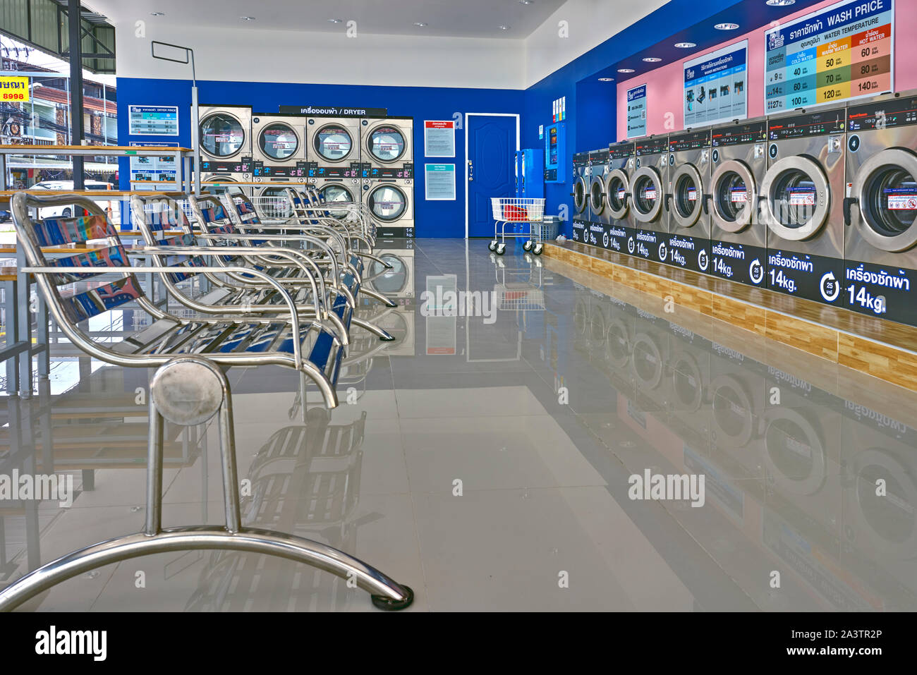 Laundromat interior with washing machines and seating for customers.Thailand Southeast Asia Stock Photo