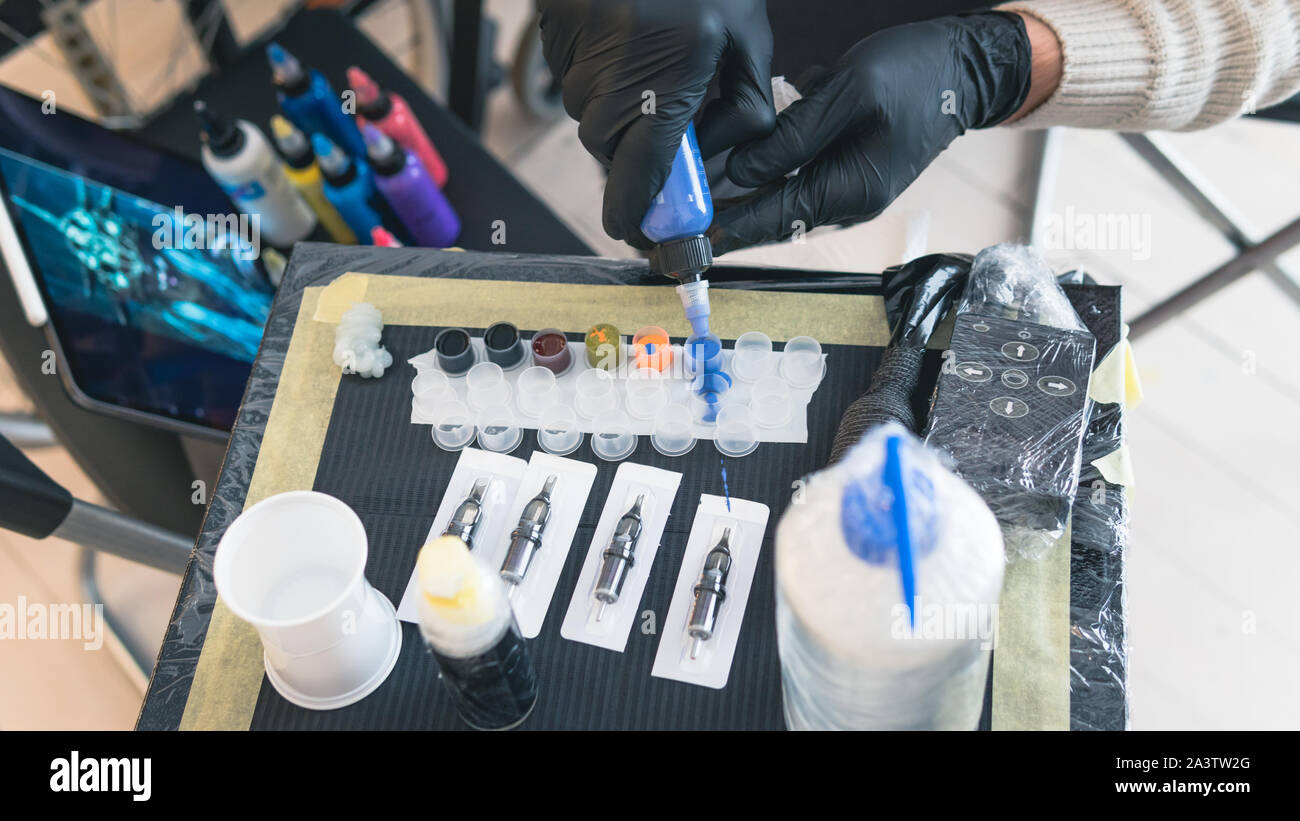 Close-up of tattoo artist work place parts and paint, machines and other equipment. Professional tattooist working tattooing in studio. Process of mak Stock Photo