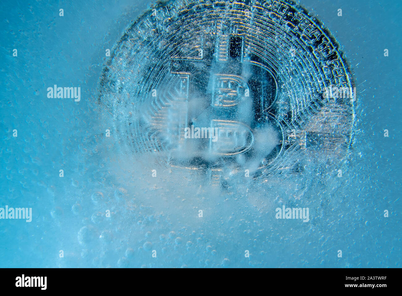 Silver Bitcoin, bit coin online digital currency frozen in the blue ice. Concept of block chain, crypto market crash. Frozen crypto money, depreciatio Stock Photo