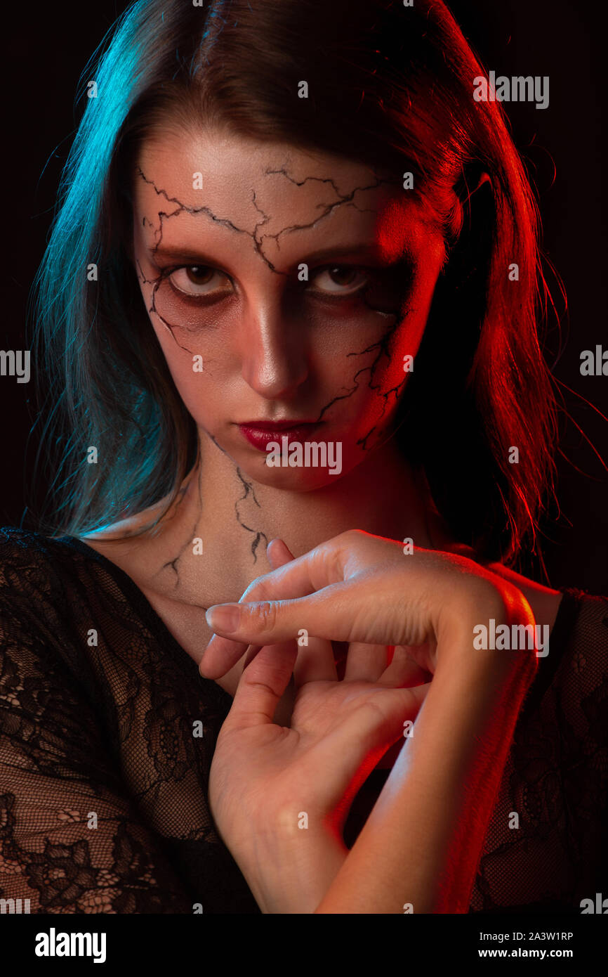 serious young woman with halloween makeup om black background with red  lighting looking at camera Stock Photo - Alamy