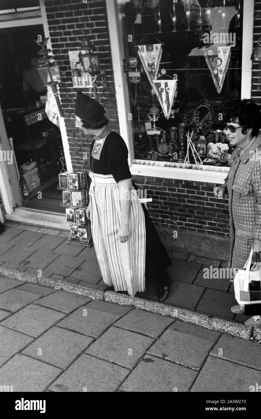 Frau in landestypischer Tracht vor einem Souvenirladen in Volendam, Niederlande 1971. Woman wearing typical array in the entrance of a souvenir shop at Volendam, The Netherlands 1971. Stock Photo