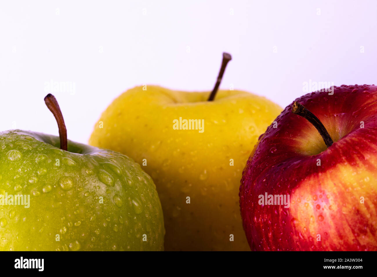 Three apples, multicolor fruits, bright background, water drops Stock Photo