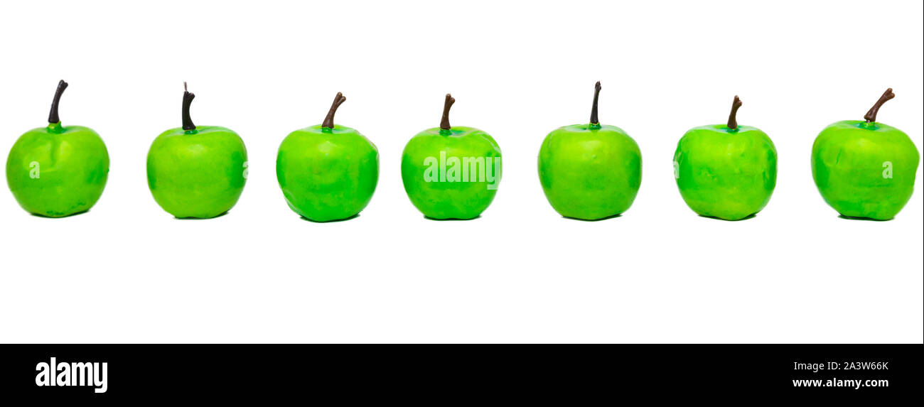 Row of artificial green apples on white background. A few green apples