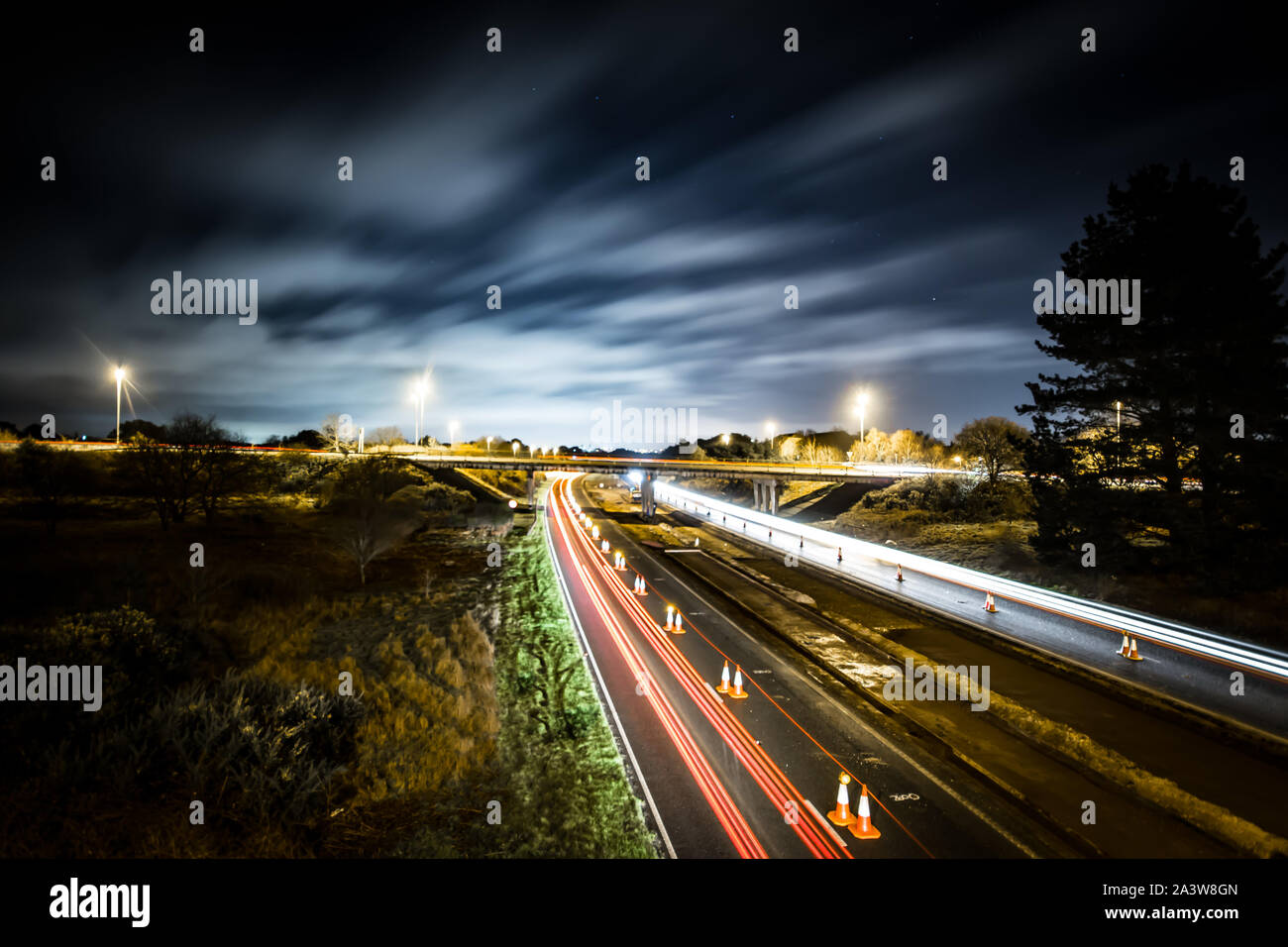 Roadworks on a dual carriageway at night showing light trails of cars passing by Stock Photo