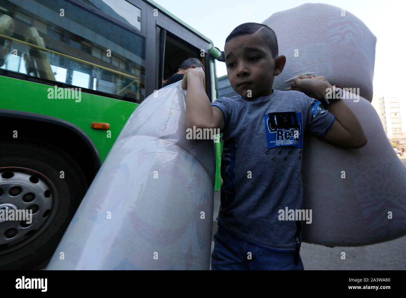 Beirut. 10th Oct, 2019. A Syrian boy carries his belongings as he goes on a homebound trip by bus from Beirut, Lebanon on Oct. 10, 2019. Around 1,000 Syrian refugees returned home from Lebanon on Thursday, the National News Agency reported. Syrians from different cities in Lebanon, including the capital Beirut, Zahle, Sidon and Tripoli, returned to their homeland by bus with the help of Lebanese General Security. Credit: Bilal Jawich/Xinhua/Alamy Live News Stock Photo
