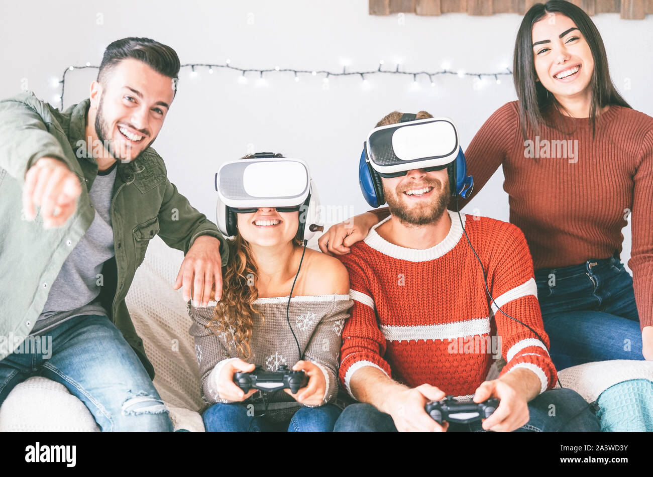 Happy millennials friends playing video games with virtual reality headset - Young people having fun with new vr online trend technology Stock Photo