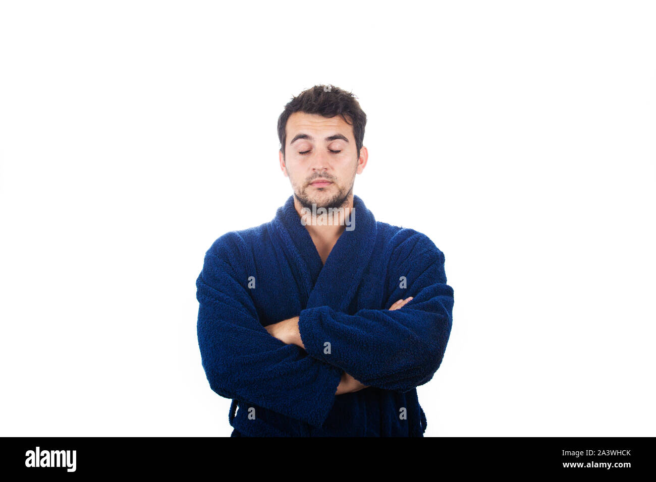Portrait of sleepy young man wears blue bathrobe with crossed arms eyes