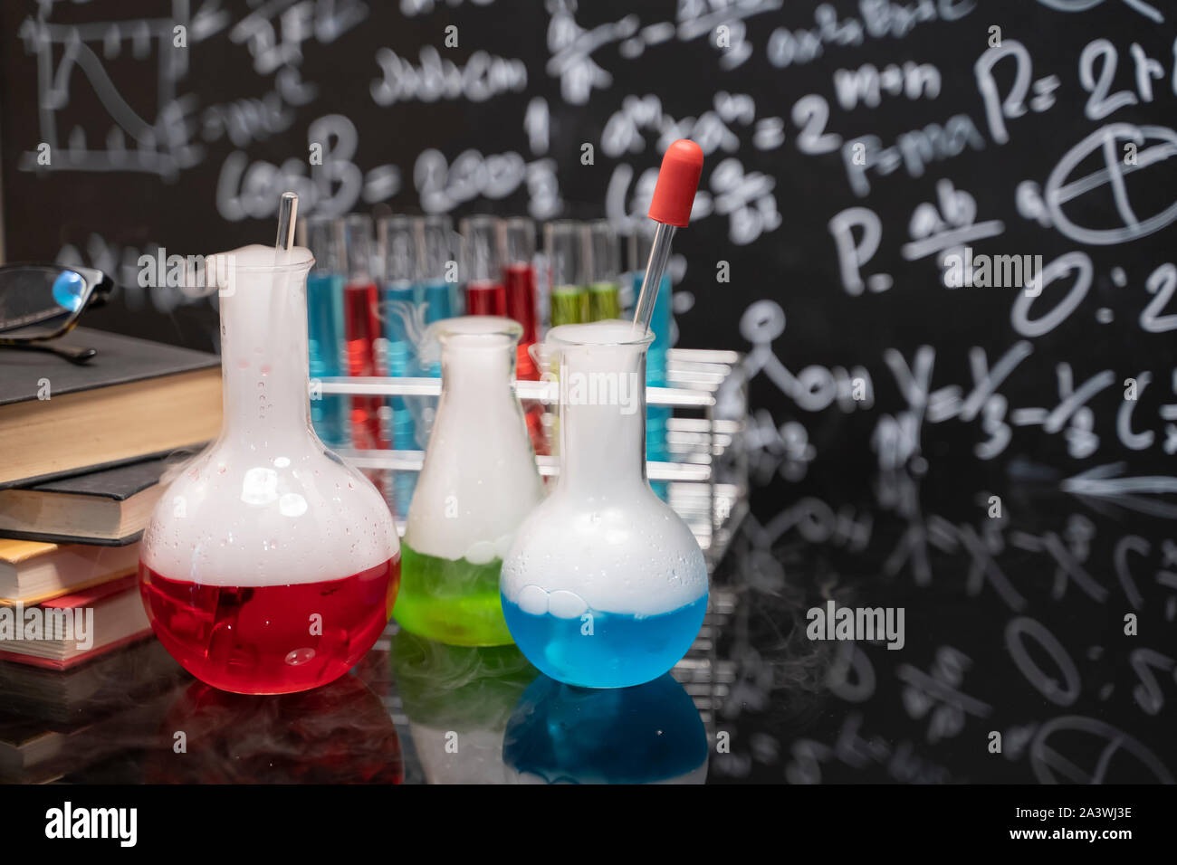 Classroom desk and drawn blackboard of chemistry teaching with books and instruments. Chemical sciences education concept. Stock Photo